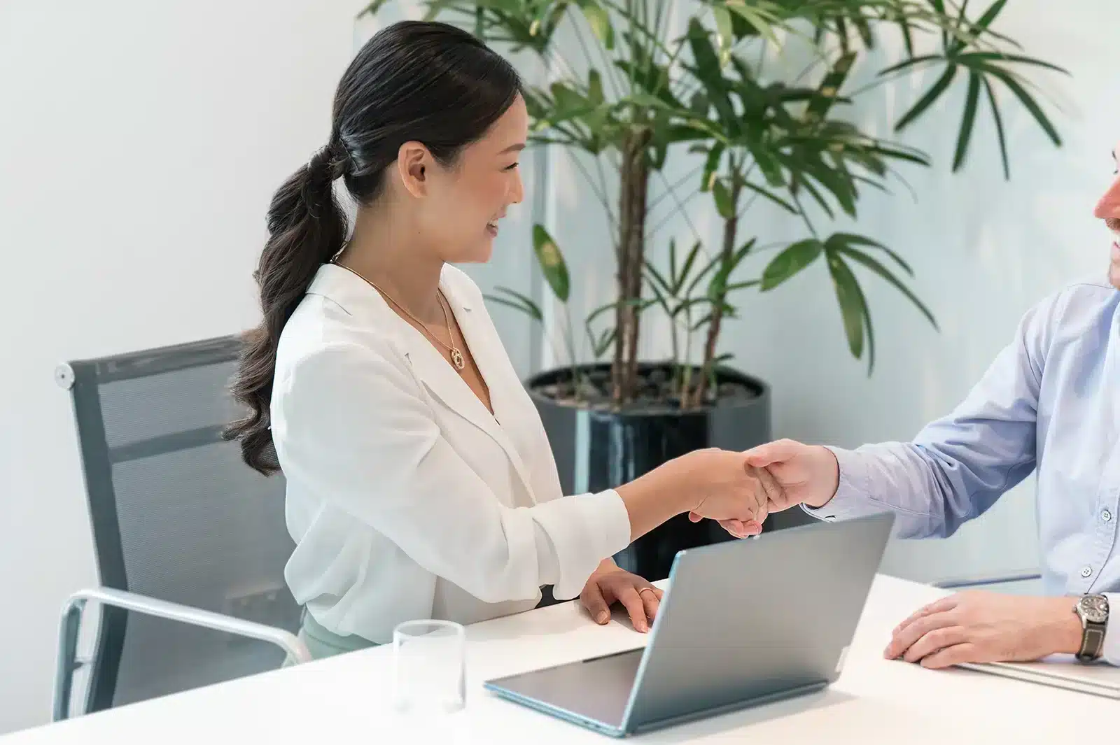 Spark Accountants adviser shaking hands with a client across a desk with a laptop